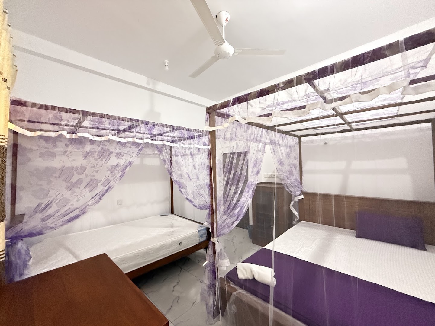 Bright bedroom with wooden beds and purple mosquito nets
