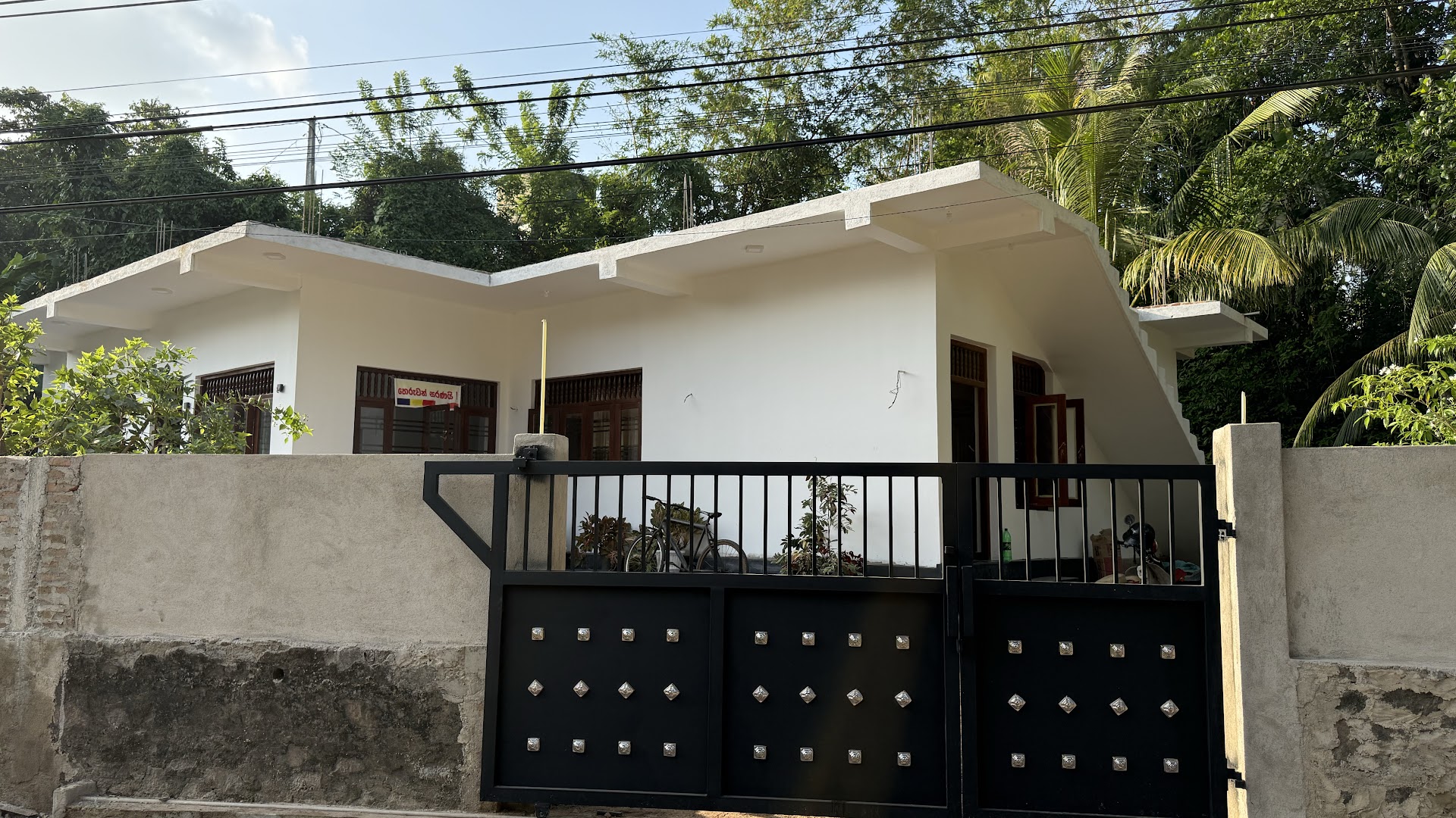 White villa behind a black geometric gate in daylight