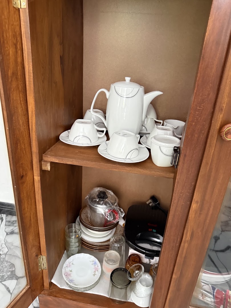 Wooden cupboard holding a tea set, plates, glasses, and cookware